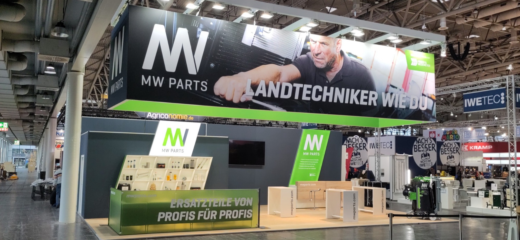 Kompakter Messestand mit beleuchtetem Deckenbanner, Produktregal und Thekenblende